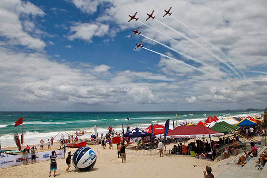 Competitors and spectators attending the Navy Australian Surf Rowers League Series witness the RAAF Roulettes fly over Surfers Paradise beach.